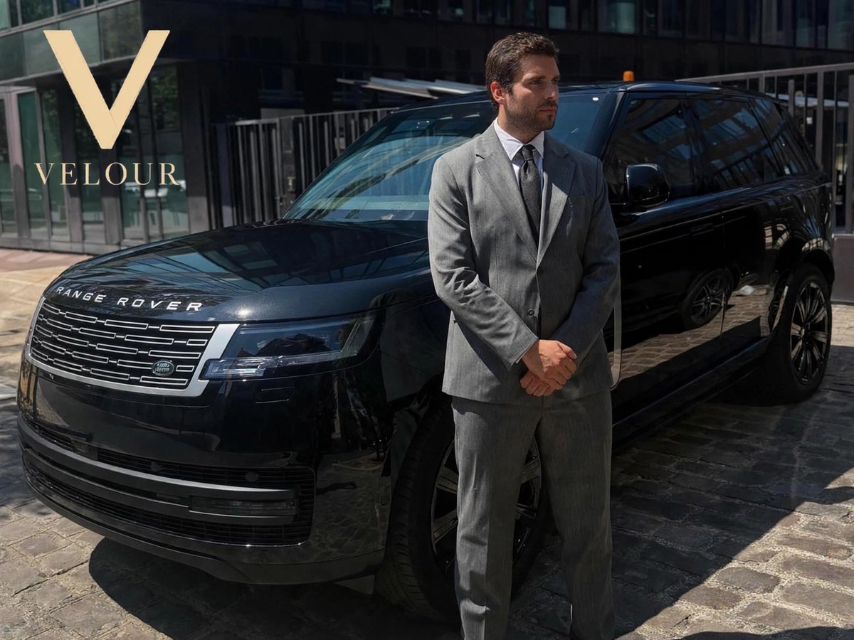 Chauffeur Velour en costume, en attente devant un Range Rover Vogue SV